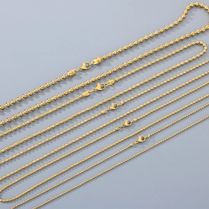 Vue macro de plusieurs tailles de colliers à billes en acier inoxydable plaqué or 18 carats