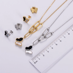 Detailed view of gold and silver butterfly pendant sets with measurement scale