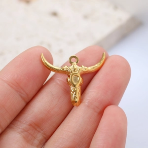 Macro shot of gold bull skull pendant held in hand showing detailed size and craft