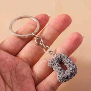 Detailed shot of resin letter D keychain with rose floral relief and silver metal ring