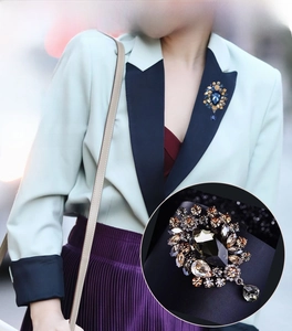 Detail of luxury teardrop blue crystal brooch with champagne stone floral setting