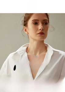 Close-up of heart moissanite three-stone necklace worn by a female model in white shirt