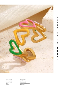 Macro detail of gold plated heart rings with colorful enamel on a textured stone surface