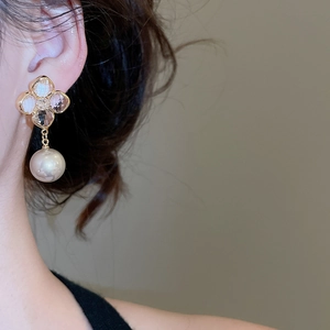 Detail of elegant gold-plated clover earrings with zircons and large white pearls