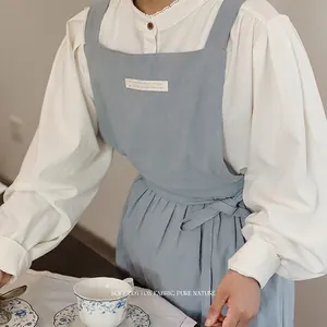 Breathable light blue cotton apron with cross straps and waist tie over white blouse