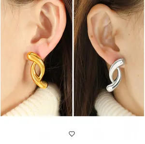 Detail of twisted gold and silver geometric earrings with high-polish metallic finish
