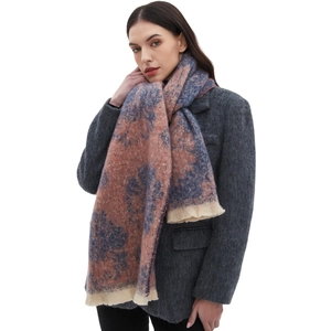 Pink and blue floral knit scarf with tassels worn by model on a white background