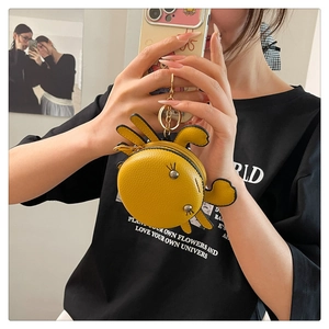 Model holding a mini yellow crab-shaped leather coin purse with golden hardware