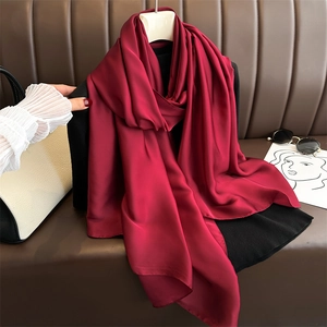 Detail of elegant dark red silk satin scarf with a glossy finish draped on a hanger