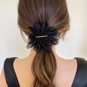 Macro detail of elegant black chiffon flower hair clip with gold metal accent on hair