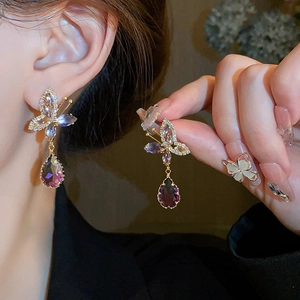 Primo piano dettagliato che mostra gli orecchini a farfalla e goccia in zircone viola sfumato.