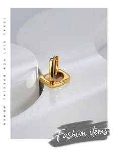 Macro view of geometric gold square hoop earrings on a professional white sculpture stand