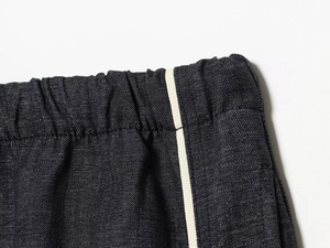 Détail de la taille en denim noir avec bandes latérales blanches et design à cordon élastique
