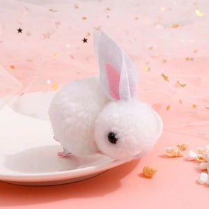 Close-up of white plush bunny hair clip with pink inner ears on white decorative plate