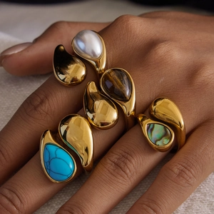 Macro view of natural stone teardrop rings in gold-plated stainless steel on hand