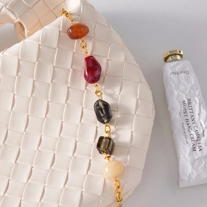 Close-up of beige woven leather bag with retro colorful beads and golden chain strap