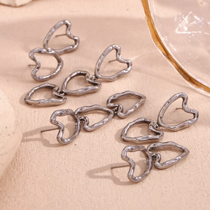 Detail of hollow heart earrings in lava metal style with dark gunmetal finish texture