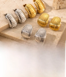 Detailed view of gold and steel screw shell pattern titanium earrings on stone base