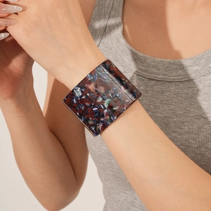 Detailed shot of a wide open acetate bangle with red blue and black marble patterns