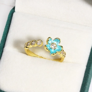 Detail of blue enamel flower ring with zircon stones in a white velvet jewelry box