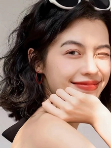 Close-up of a model wearing glossy red circular hoop earrings with a retro aesthetic