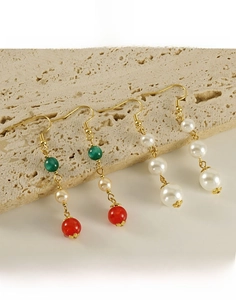 Vue détaillée de boucles d'oreilles pendantes en acier titane doré 18 carats avec perles