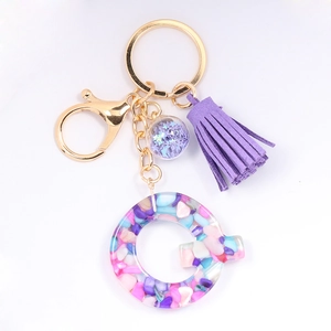 Detail of resin letter C keychain with colorful stones, purple tassel, and golden hardware