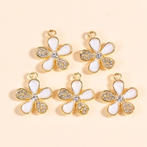 Detail of five gold flower pendants with white enamel and sparkling crystal stones