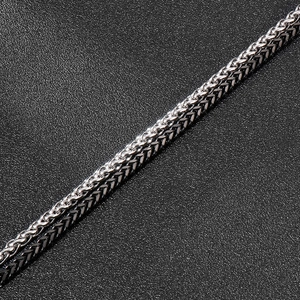 Detail of silver and gunmetal woven stainless steel chains on black leather background