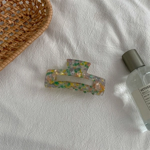 Detail of medium acetate hair claw with yellow green and pink floral tortoiseshell pattern