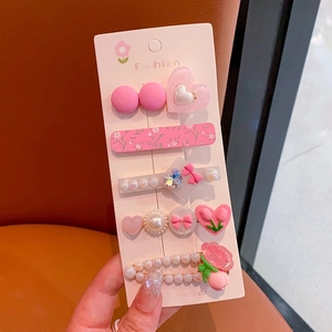 Detailed view of pink floral and pearl hair clips set on a fashion display card