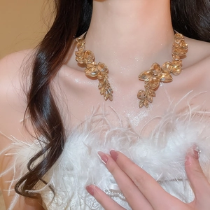 Detail of elegant gold-tone leaf collar necklace with champagne teardrop crystals on model