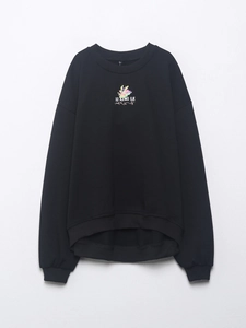 Detalle de sudadera negra de cuello redondo con estampado de dragón colorido y letras