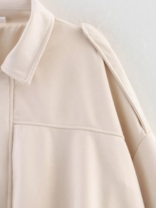 Detailed macro view showing the beige suede texture and lapel stitching on the bomber jacket