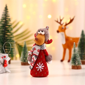 Detail of Christmas reindeer doll in red knit dress with plush hat on festive background