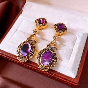 Macro shot of vintage gold oval earrings with purple stones on velvet jewelry box