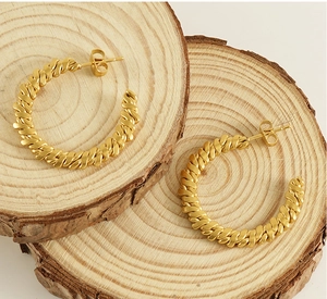 Detail of gold 18K stainless steel hoop earrings with twisted vintage texture
