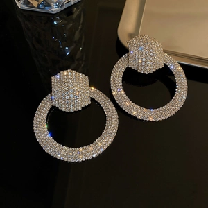 Close-up of oversized silver-needle hoops with sparkling pavé rhinestones in champagne gold
