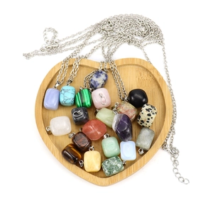 Assorted natural stone rectangular pendants on silver chains displayed in a wooden tray