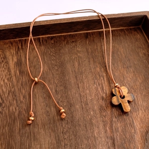 Close-up of vintage tiger eye stone cross pendant with adjustable braided cord and gold beads
