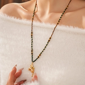 Detail van kralenketting met gouden tijger hanger op een witte trui achtergrond