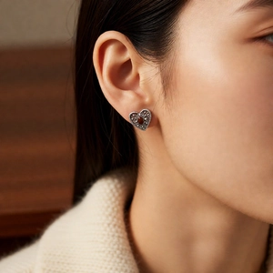 Close-up of vintage heart earrings with red gemstones and marcasite details on model