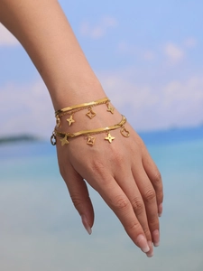 Détail d'un bracelet double couche doré avec trèfles à quatre feuilles au poignet