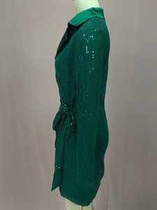 Dettaglio di un abito verde con paillettes con colletto a rever e lacci in vita