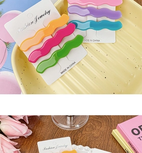 Flat lay of colorful wavy macaron hair clips on a ceramic plate with tulip flowers