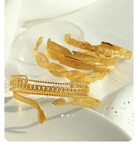Detail of stacked 18K gold plated Cuban chain bracelets with feather and snake textures