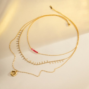 Three-layer gold stainless steel necklace with red beads, fringe, and a sunburst coin pendant