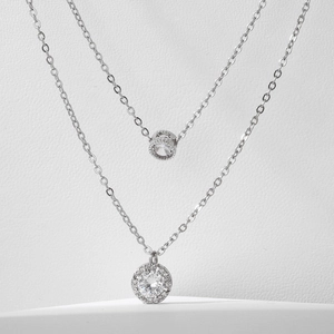 Macro detail of silver double-layer necklace with circular and cylindrical zircon pendants