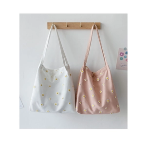 Detail of white and pink tote bags featuring delicate daisy embroidery on soft canvas fabric