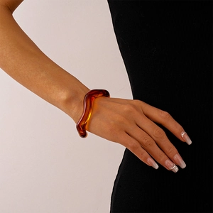 Close-up of wavy amber acrylic resin bangle showing irregular geometric design